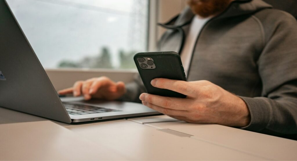 Travel manager using a phone and laptop to coordinate FIFO crew bookings