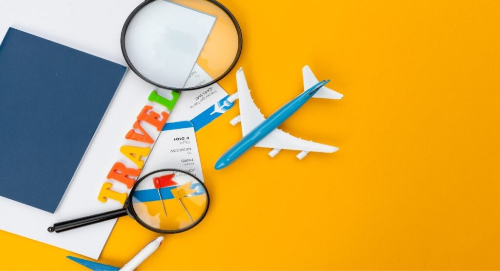 Travel planning flat lay with a toy airplane, boarding pass, passport, magnifying glasses, and colorful letter tiles on an orange background