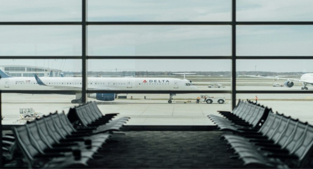 Empty airport gate seating at Detroit Metropolitan Airport with a Delta Airlines aircraft on the tarmac