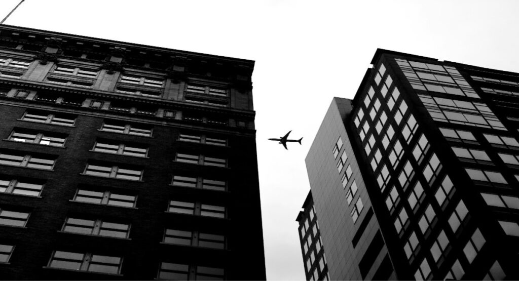 A commercial aircraft flying over downtown city buildings