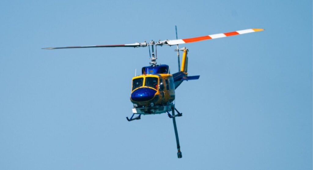 Helicopter in flight against a clear blue sky, used for charter transport in fly-in, fly-out crew logistics