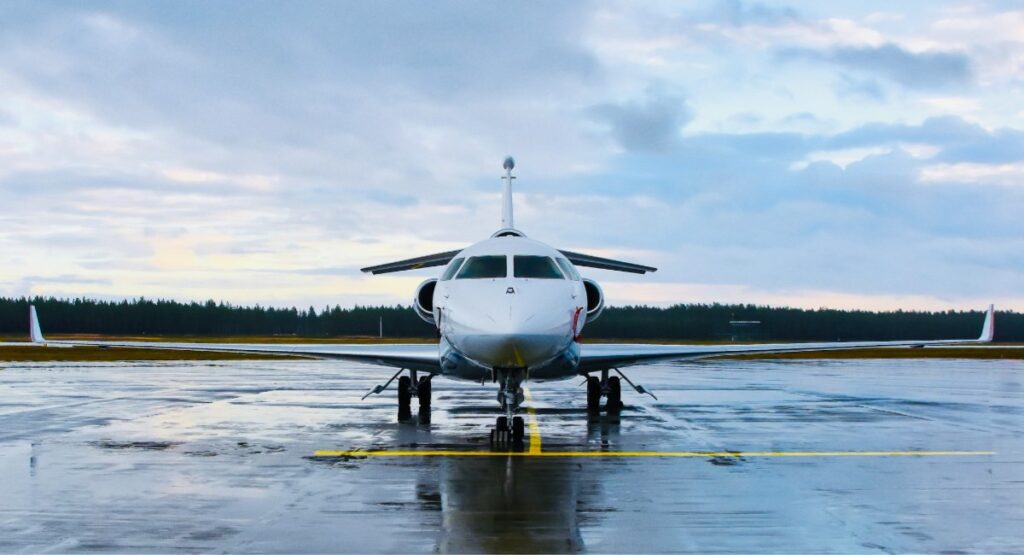 A white private jet parked on a wet runway at a regional airport