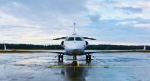 A white private jet parked on a wet runway at a regional airport