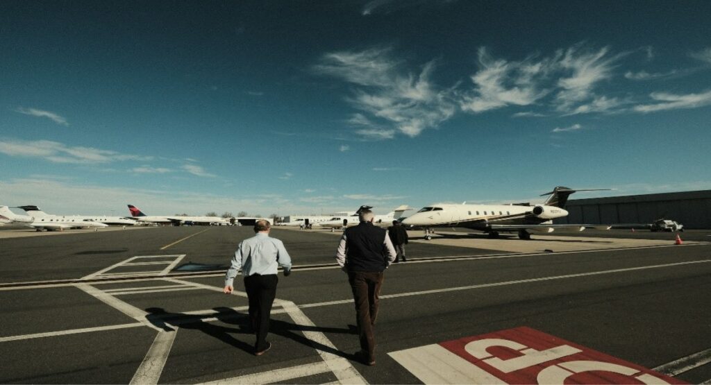 Crew travel coordinators on airport tarmac with corporate aircraft fleet