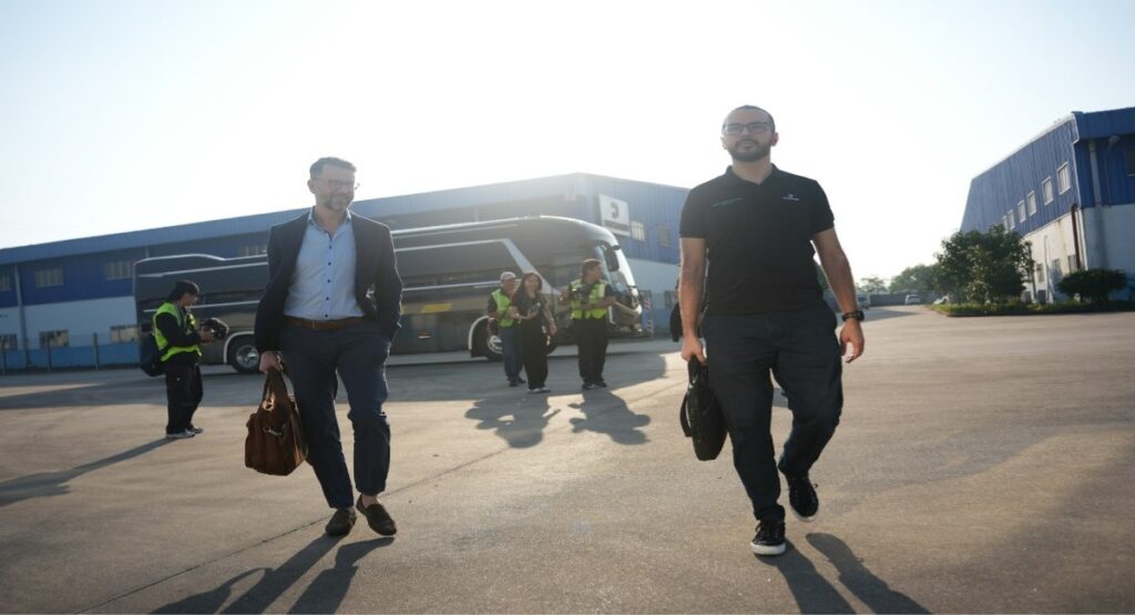 Two business travelers walking across a tarmac with a coach bus in the background