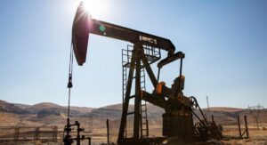 A towering oil derrick stands prominently in the Permian Basin landscape on a bright, sunny day.
