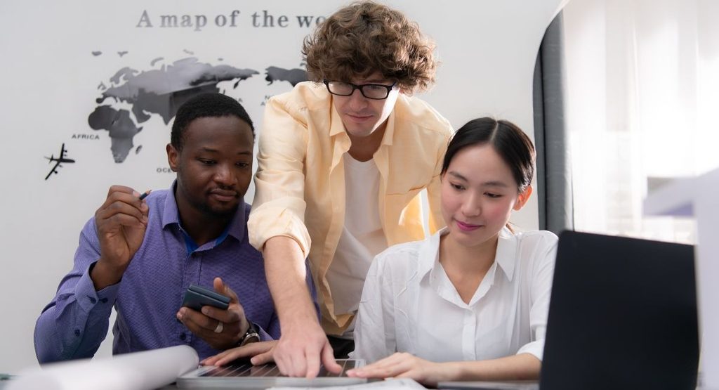Three colleagues planning corporate travel and budgeting in an office setting